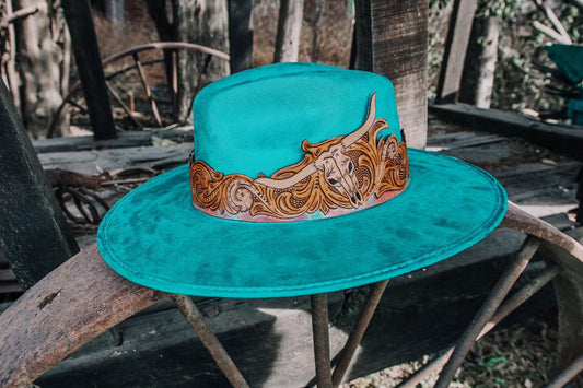 Sombrero textil acabado en gamuza con toquilla artesanal de cuero cincelada y pintada a mano.